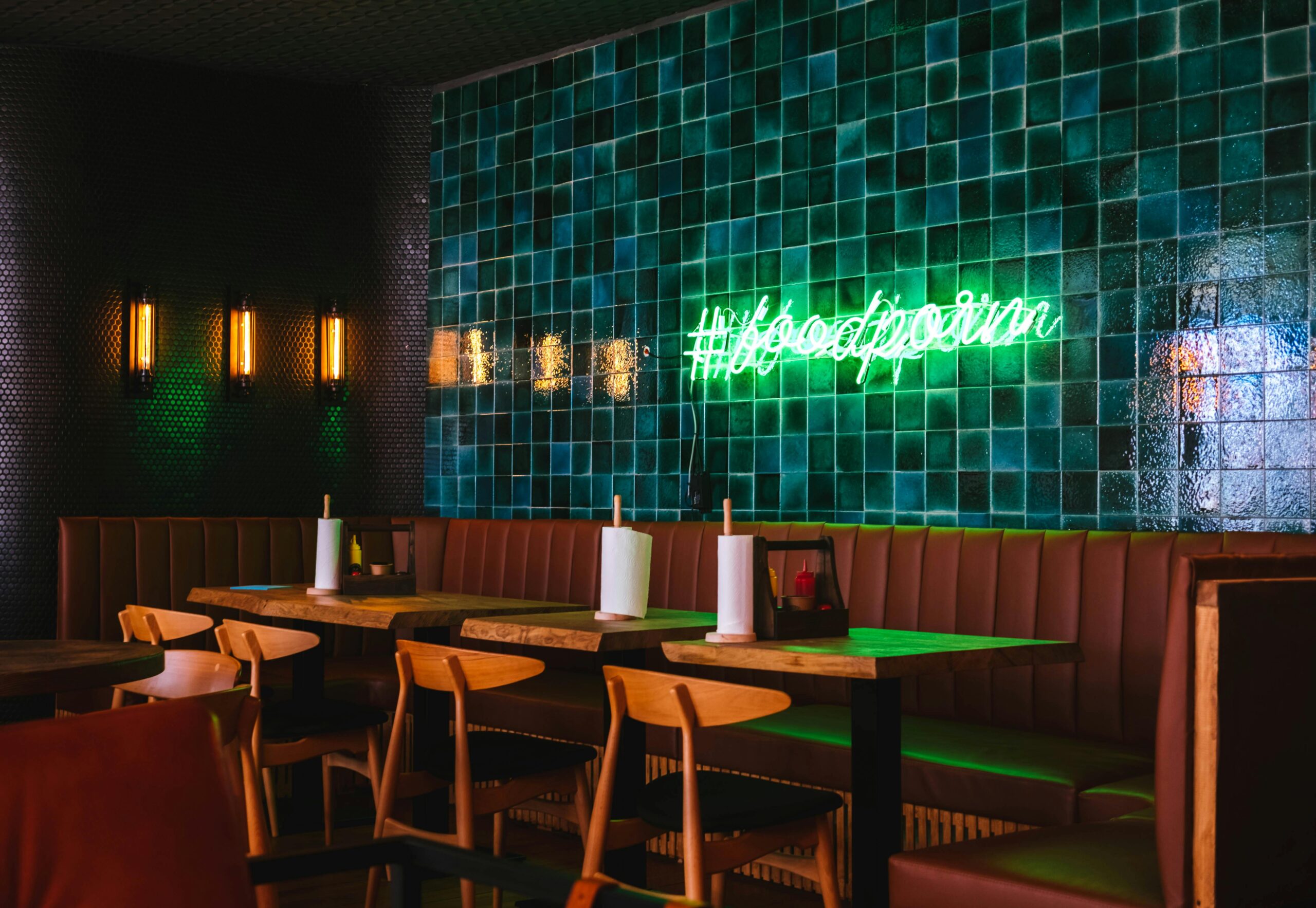 Contemporary restaurant interior with green tile wall and neon sign in Sochi, Russia.